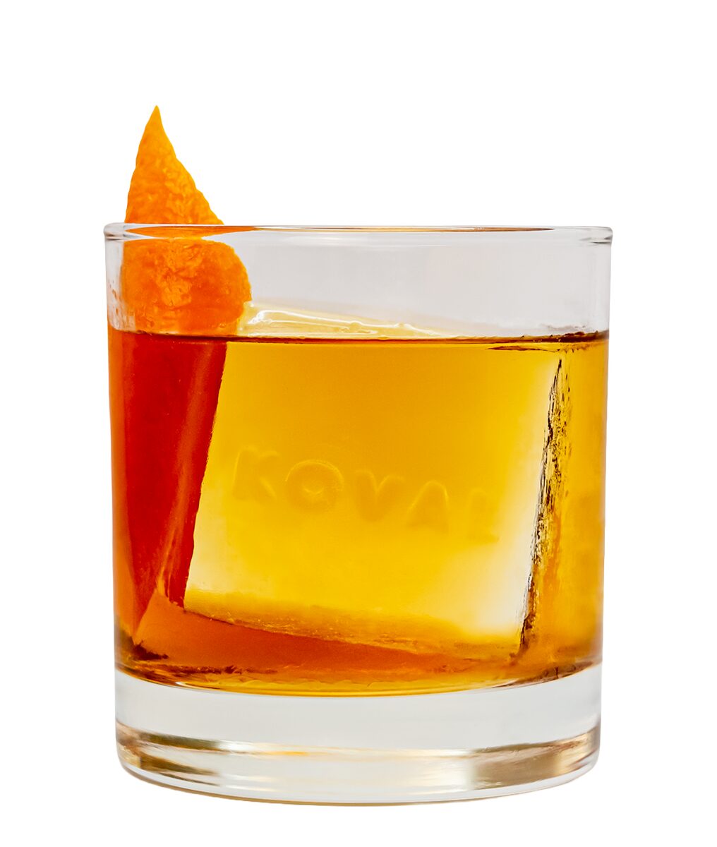 KOVAL Bourbon Old Fashioned on white with orange peel and a KOVAL ice cube